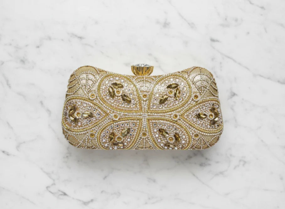 Gold clutch bag with intricate designs on a marble surface